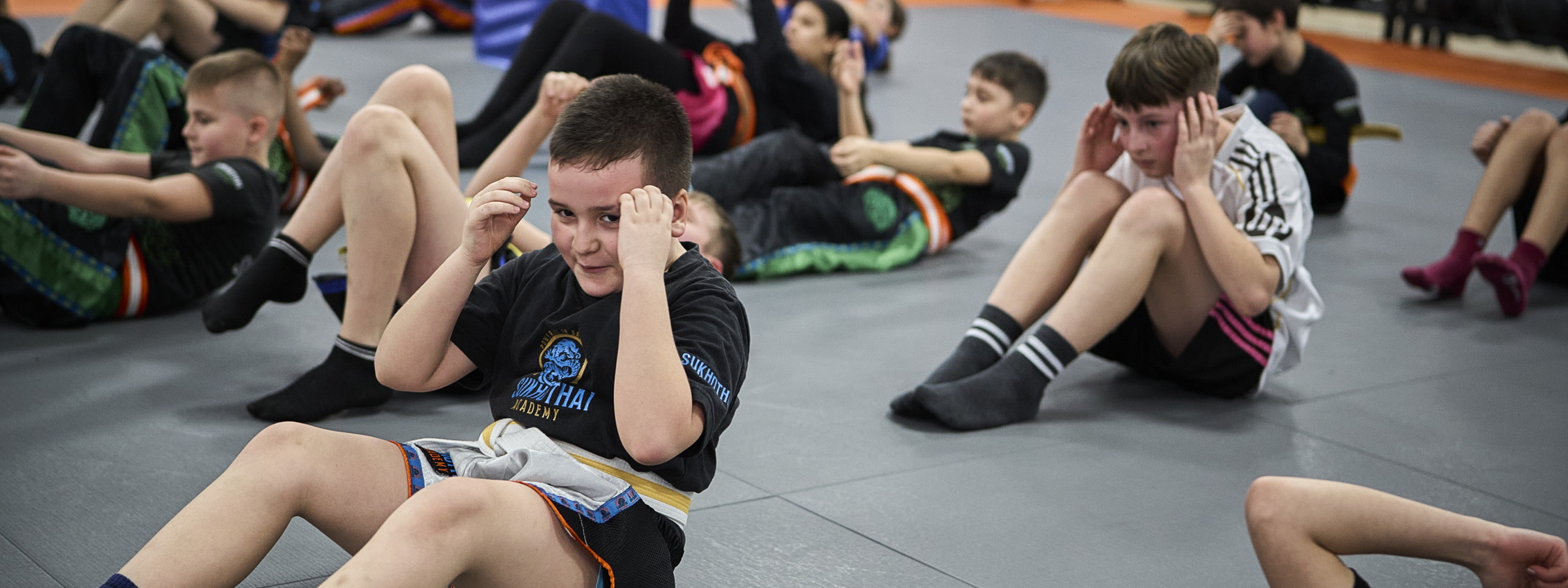 Eine ganze Kindergruppe macht gemeinsam Sit-ups auf der Matte.