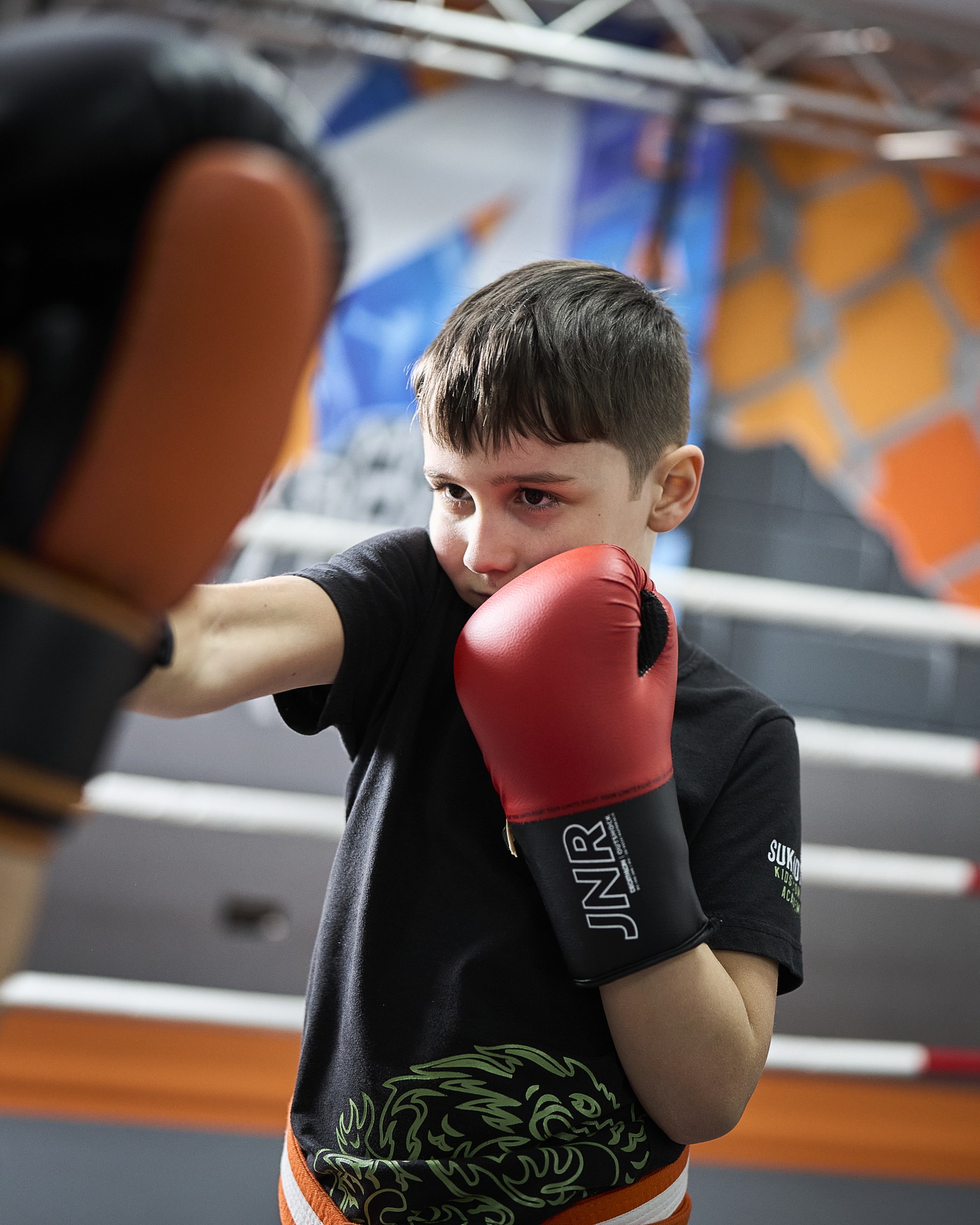 Ein Junge mit roten Boxhandschuhen hält konzentriert die Deckung.